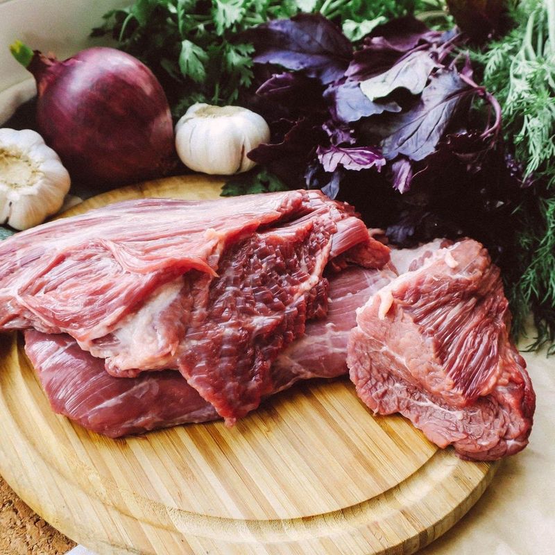 Raw beef on a wooden board with garlic and onion