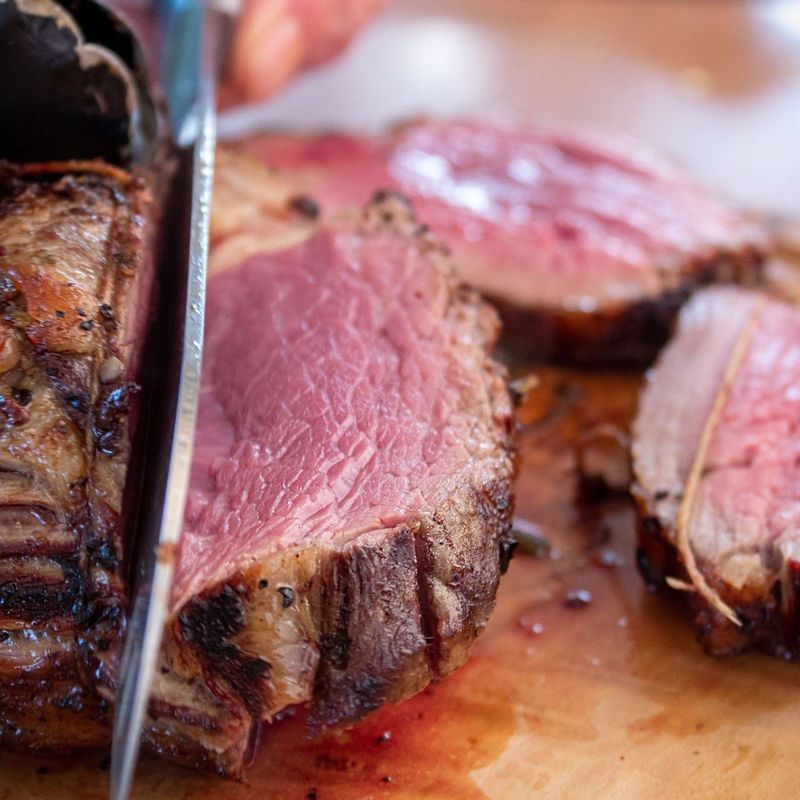 A cooked steak being sliced to show a pink centre